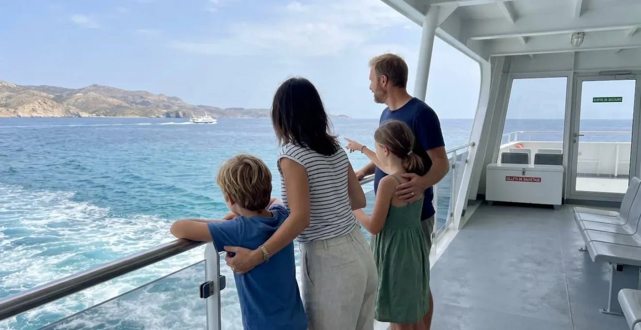 Une famille de quatre personnes vue de dos regarde ensemble la mer Méditerranée depuis le pont d'un ferry moderne par une journée ensoleillée